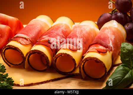 Käse und Schinken auf Schneidebrett auf hölzernen Tisch Stockfoto