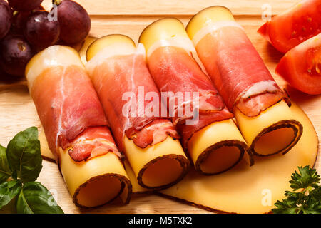 Käse und Schinken auf Schneidebrett auf hölzernen Tisch Stockfoto