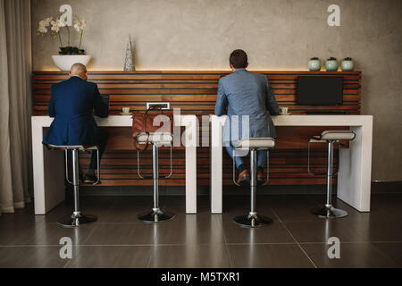 Ansicht von hinten geschossen von zwei Geschäftsleute bei free Internet service Counter sitzen in Airport Lounge. Geschäft Leute an Cyber Corner in den internationalen Flughafen Stockfoto
