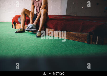 7/8 Schuß von Mann an einem wall Kletterhalle Anwendung magnesium Chalk Pulver auf die Hände aus der Tasche. Stockfoto