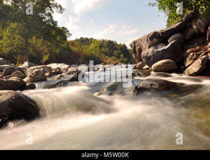 Schnell fließendes Wasser einen Fluss hinunter mit langer Belichtung, weichem Wasser und Felsen. Aufgenommen auf der Insel Korsika Stockfoto
