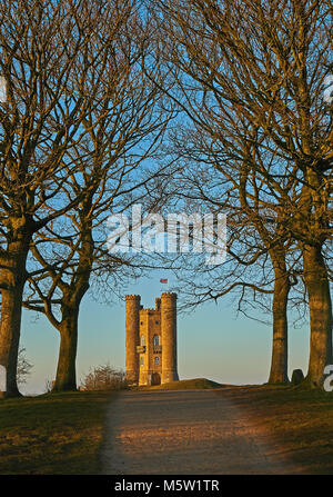 Broadway Tower auf Fisch Hill, dem zweithöchsten Punkt in den Cotswolds wird durch vier Laubbäume auf einer winterlichen Nachmittag gerahmt Stockfoto
