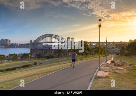 Man joggen in Barangaroo finden mit der Sydney Harbour Bridge im Hintergrund, Sydney, New South Wales, Australien Stockfoto