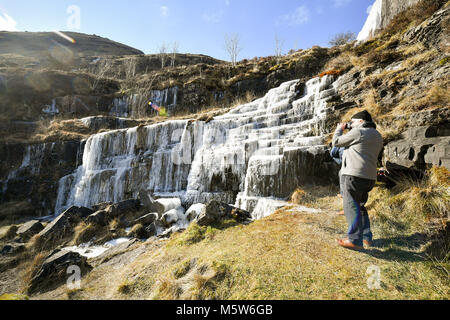 Menschen fotografieren sie Einen gefrorenen Wasserfall in der Nähe von Pen y Fan Berg auf Brecon Beacon National Park, Wales, in einigen Teilen des Vereinigten Königreichs eingerichtet sind, fühlen sich kälter als die Arctic Circle als eisige Temperaturen in der kommenden Woche fortsetzen. Stockfoto