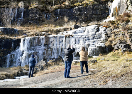 Menschen fotografieren sie Einen gefrorenen Wasserfall in der Nähe von Pen y Fan Berg auf Brecon Beacon National Park, Wales, in einigen Teilen des Vereinigten Königreichs eingerichtet sind, fühlen sich kälter als die Arctic Circle als eisige Temperaturen in der kommenden Woche fortsetzen. Stockfoto