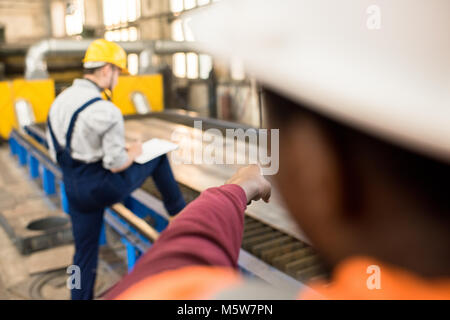 Multi-ethnischen Team von Technikern tragen hardhats und einheitliche Durchführung der Inspektion bei der Produktion moderner Anlagen, einer von ihnen Nec unter Stockfoto