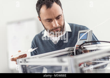 Angenehmer junger Mann in 3D Drucker suchen Stockfoto