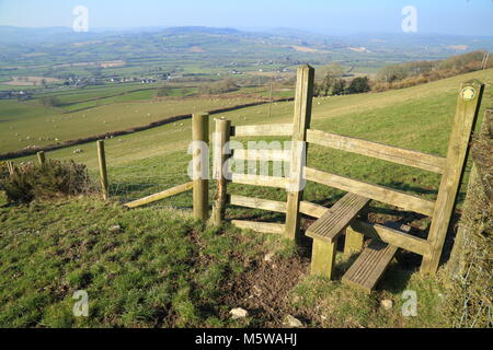 Schritten über einen holzzaun als Teil einer öffentlichen Fußweg auf musbury Hill mit wunderschönem Blick auf Ax Tal in East Devon AONB Stockfoto