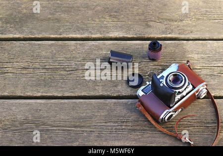 Alten retro Kamera in eine braune Ledertasche und einem fotografischen Film Roll auf verdorrte Holzplanken, Vintage Style Stockfoto