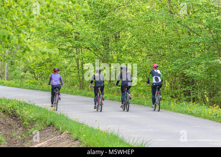 Junge Frauen, die auf Fahrrädern in einer Straße in einem Laubwald Stockfoto