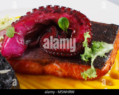 Gourmet-Lachs mit Oktopus, schwarzem Reis und gelber Sauce, Feinschmeckerpräsentation. Stockfoto