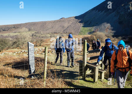 Ramblers Gruppe von Wanderern auf Fußweg Stil durch Coedydd Aber National Nature Reserve Schiefer unterzeichnen. Abergwyngregyn, Gwynedd, Wales, Großbritannien, Großbritannien Stockfoto