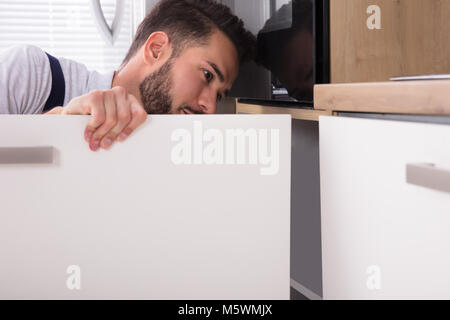 Junge Handwerker zur Festsetzung Waschbecken Tür in der Küche Stockfoto