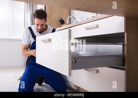 Junge Handwerker in der gesamten Installation Schublade in der Küche Stockfoto