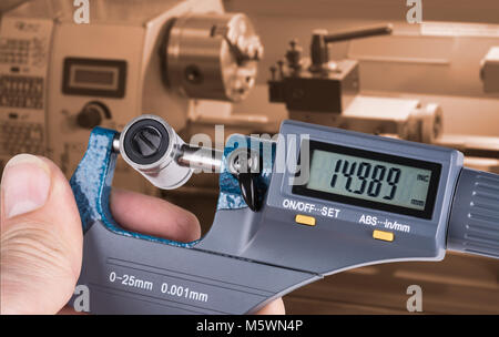 Detail der Hand Facharbeiter mit digitalen Mikrometerschraube messen. Die genaue Messung der lineare Lager durch Messen Werkzeug- und Drehmaschine im Hintergrund. Stockfoto