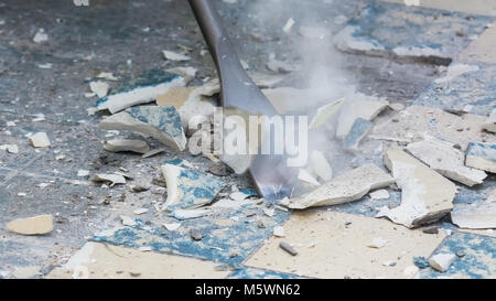 Ausbau der alten Fußboden bei der Renovierung von Wohnungen. Manuelle Arbeit Idee. Close-up von Demolition Hammer, Meißel, Fragmente von keramischen Fliesen und Funken. Stockfoto