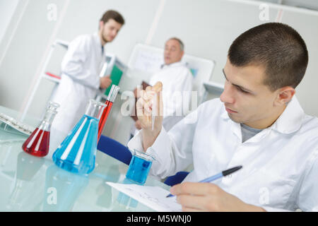 Männliche medizinisches Labor junge Forscher führt Tests mit blauer Flüssigkeit Stockfoto