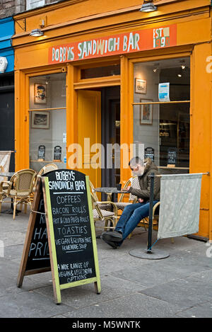 Ein Kunde außerhalb Bobby's Sandwich Bar in Edinburgh, Schottland, Großbritannien sitzen. Stockfoto