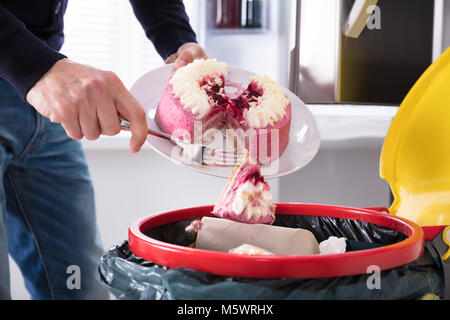 Nahaufnahme einer menschlichen Hand Kuchen In Papierkorb werfen Stockfoto