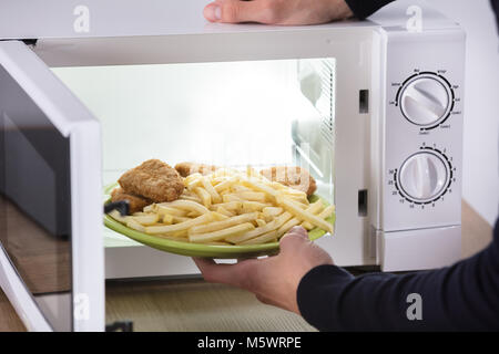 Nahaufnahme von einer Person Hand gebratene Nahrung in der Mikrowelle Stockfoto