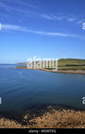 Blick auf die Kimmeridge Bay Seascape, Dorset, England. Blick auf den blauen Ozean, die grünen Hügel dahinter und den blauen Himmel mit Wolken. Stockfoto