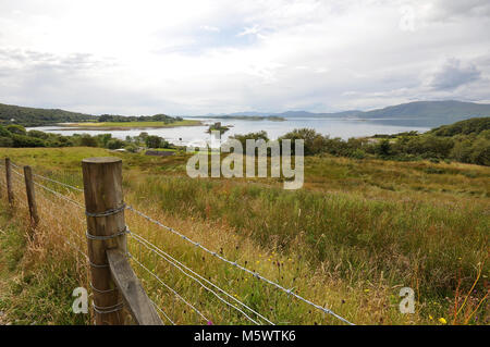 Schloss auf einer Insel mit Spiegelung, bewölktem Himmel und Bergen dahinter. Grass Foreground, Stalker Castle, Loch Laich, Argyll, Schottland Stockfoto