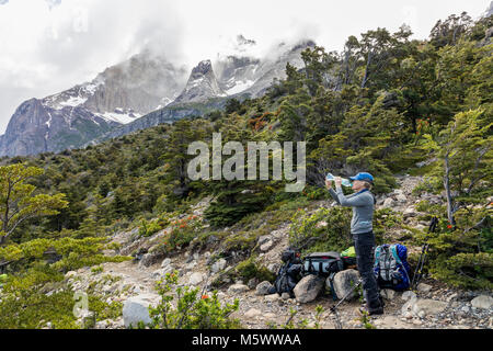 Weibliche trekker Pausen für Wasser zu trinken; Cordillera Paine darüber hinaus; Torres del Paine Nationalpark, Chile Stockfoto