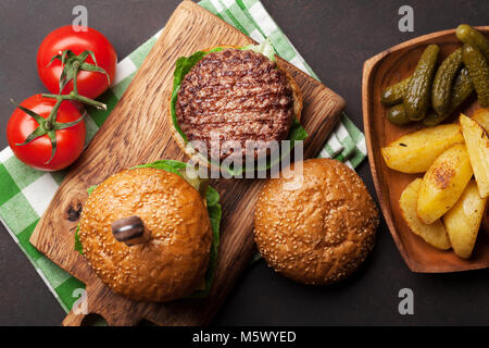 Lecker gegrilltes home Burger mit Rindfleisch, Tomaten, Käse, Gurken und Salat gemacht. Ansicht von oben Stockfoto