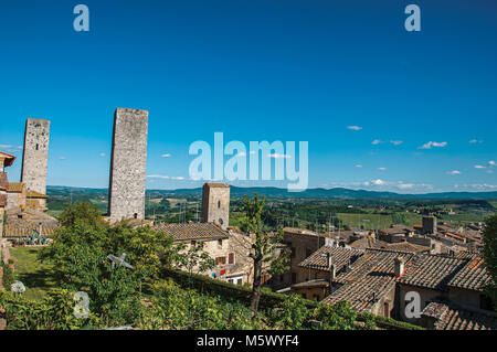 Aussicht auf die Dächer und Türme mit grünen Hügeln im Hintergrund in San Gimignano. Eine mittelalterliche Stadt mit mehreren Türmen. Stockfoto