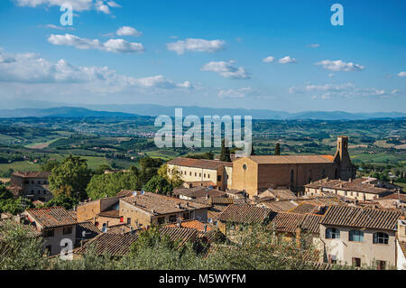 Überblick über Dächer und Kirche mit grünen Hügeln und blauer Himmel in San Gimignano. Eine mittelalterliche Stadt mit mehreren Türmen. Stockfoto