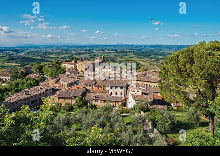 Überblick über Dächer und Kirche mit grünen Hügeln und blauer Himmel in San Gimignano. Eine mittelalterliche Stadt mit mehreren Türmen. Stockfoto