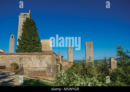 Aussicht auf die Dächer und Türme mit Bäumen und blauen sonnigen Himmel von San Gimignano. Eine mittelalterliche Stadt mit mehreren Türmen. Stockfoto