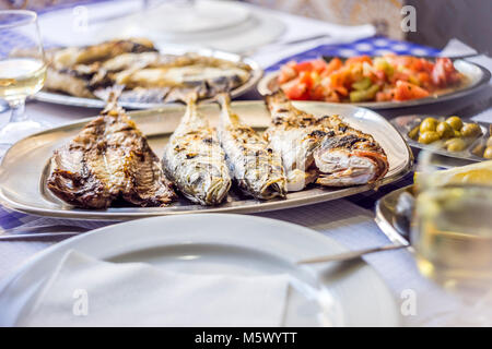 Fisch fest: Sea Bass, golden, Makrelen mit Tomatensalat, grünen Oliven und Wein, Portugal begleitet Stockfoto