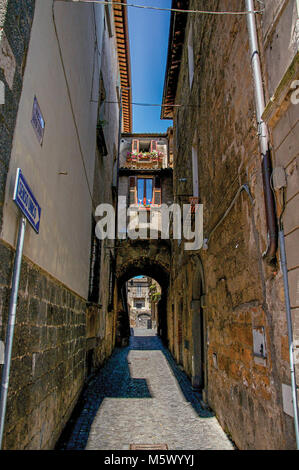 Überblick über eine schmale Gasse mit alten Gebäuden und Verkehr in der Stadt Orvieto, eine schöne und gut erhaltene mittelalterliche Stadt. Stockfoto