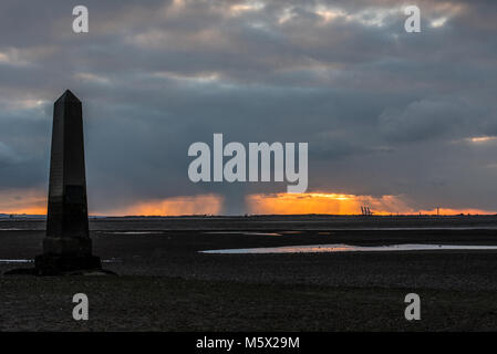 Schnee kam in der Abenddämmerung im Southend Borough an, als die Sonne hinter dem Crowstone in Chalkwell, Essex, Großbritannien unterging. Themsenmündung bei Ebbe. PLA-Grenzmarkierung Stockfoto