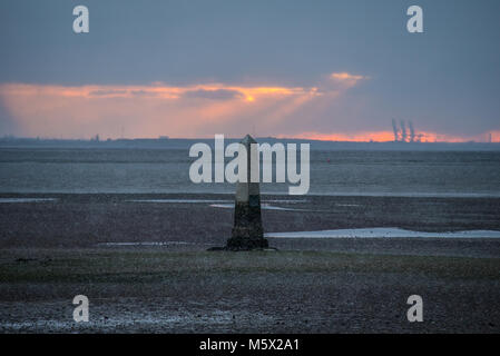 Schnee kam in der Abenddämmerung im Southend Borough an, als die Sonne hinter dem Crowstone in Chalkwell, Essex, Großbritannien unterging. Themsenmündung bei Ebbe. PLA-Grenzmarkierung Stockfoto