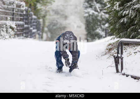 Ashford, Kent, Großbritannien. 27 Feb, 2018. UK Wetter: Tier aus dem Osten. Ein Kind macht einen Schneeball. Foto: Paul Lawrenson/Alamy leben Nachrichten Stockfoto