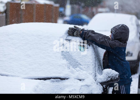 Ashford, Kent, Großbritannien. 27 Feb, 2018. UK Wetter: Ein 11 Jahre alter Junge sammelt Schnee von oben ein Auto als "Tier aus dem Osten' führt durch ländliche Kent. Foto: Paul Lawrenson/Alamy leben Nachrichten Stockfoto