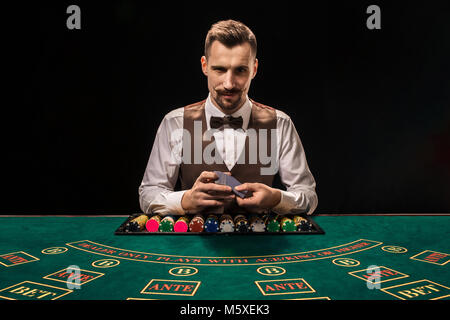 Stattliche Händler mischen die Karten Deck und Chips auf grünen Tisch Stockfoto