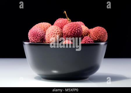 Litschi Obst in einer Schüssel auf dunklem Hintergrund isoliert Stockfoto