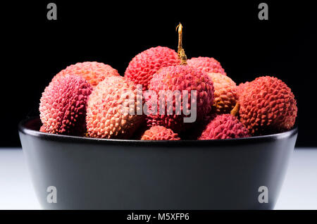 Litschi Obst in einer Schüssel auf dunklem Hintergrund isoliert Stockfoto