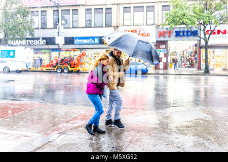 Bronx, USA - Oktober 29, 2017: Straße Straße in Fordham Höhen Zentrum mit Geschäften, New York City, NEW YORK CITY bei Tag, starker Regen, nasse glückliches Paar walking Stockfoto