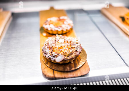 Nahaufnahme von zwei kleinen süßen gebackener Pfirsich pflaume Nektarine Torten mit Mandel Mutter Flocken golden gourmet Bakery Cafe auf dem Display Fach Stockfoto