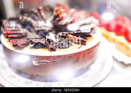 Viele Schokolade Kuchen in Bäckerei shop shop mit Erdbeer Sahne Dekorationen, Späne hinter Glas, Bokeh Stockfoto