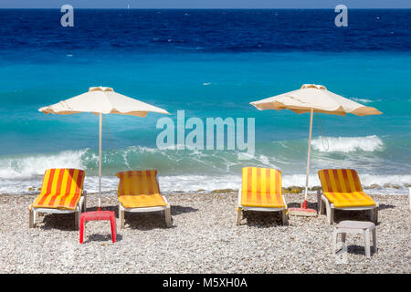 Rhodos, Griechenland, Sonnenliegen und Sonnenschirme am Strand von Rhodos Stadt. Stockfoto