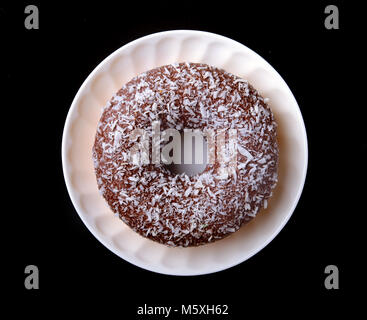 Hausgemachten Krapfen in der Glasur, bunten Streuseln auf schwarzem Hintergrund. Stockfoto