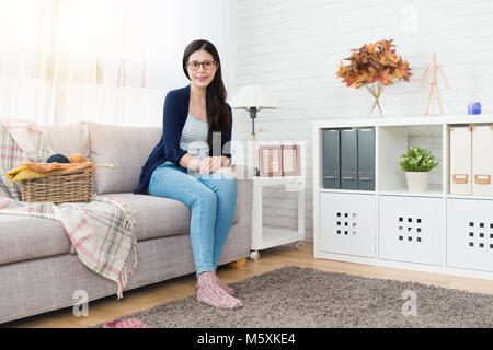 Schöne asiatische Frau sitzt auf einem Sofa bereit zu stricken für Winter im Wohnzimmer zu Hause kommen machen Stockfoto