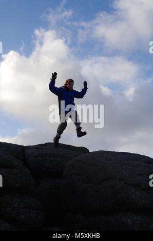 Junge männliche Hill Walker ontop der Granit Tor, von Haytor an einem windigen Wintertag. Nationalpark Dartmoor, Devon, Großbritannien. Stockfoto