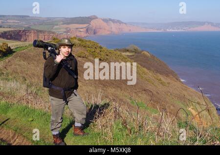 Junge schöne Vogelbeobachter mit Leica Spotting Teleskop. Auf dem South West Coast Path bei Budleigh Salterton, East Devon, Großbritannien. Jurassic Coast. Stockfoto