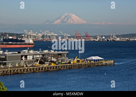 WA13730-00...WASHINGTON - Blick auf Mt. Rainier, Elliott Bay und die Kräne zum Be- und Entladen der Containerschiffe an der Seattle Waterfront. 2017 Stockfoto